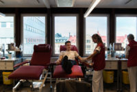 Sjuksköterska tappar blod på kille som sitter i röd stol